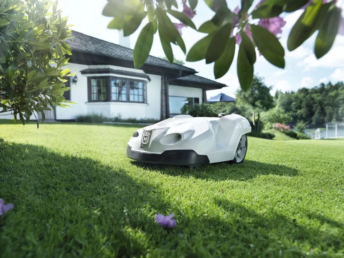 Robotic lawn mower on a green lawn in front of a house